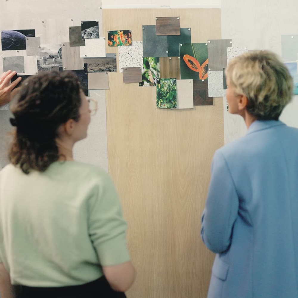 Elise Bylo, Moduleo Design Manager, po lewej i Cindy Van Moorleghem, Moduleo Brand Director, po prawej, widziana od tyłu, w trakcie ćwiczenia na tablicy nastrojów.